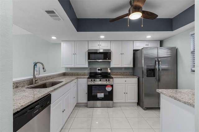 kitchen with light stone counters, stainless steel appliances, ceiling fan, sink, and white cabinetry