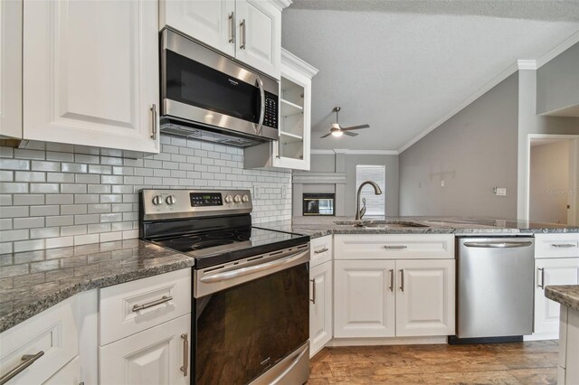 kitchen featuring light wood-type flooring, ceiling fan, stainless steel appliances, decorative backsplash, and ornamental molding