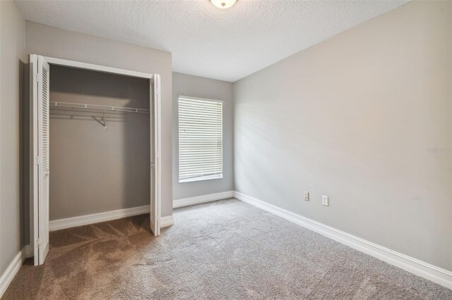 unfurnished bedroom featuring a closet, carpet flooring, and a textured ceiling