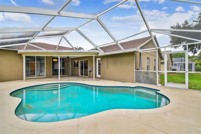 view of swimming pool featuring a patio, glass enclosure, and ceiling fan