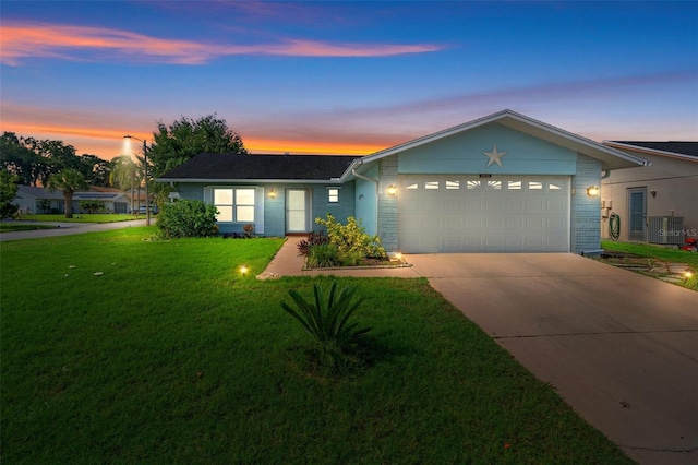 ranch-style house featuring a lawn, a garage, and central air condition unit