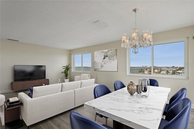 dining room featuring a notable chandelier, visible vents, and wood finished floors