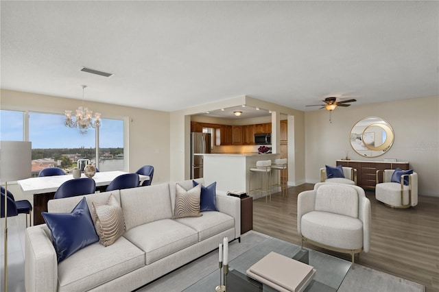 living room featuring light wood-type flooring and ceiling fan with notable chandelier