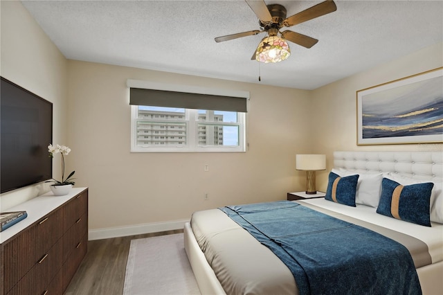 bedroom featuring ceiling fan, a textured ceiling, and wood-type flooring