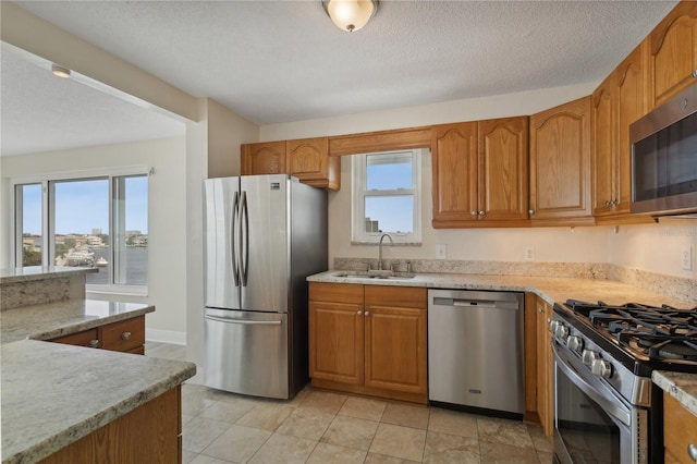 kitchen featuring light tile patterned floors, sink, stainless steel appliances, and a healthy amount of sunlight