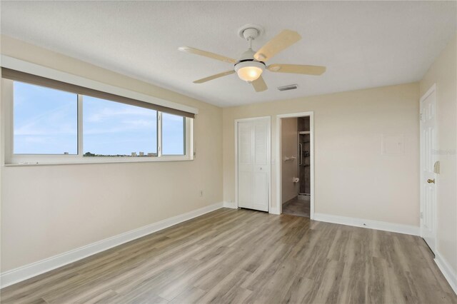 unfurnished bedroom featuring visible vents, baseboards, ceiling fan, light wood-type flooring, and connected bathroom