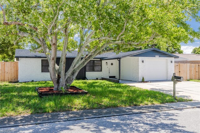 single story home featuring a garage and a front lawn