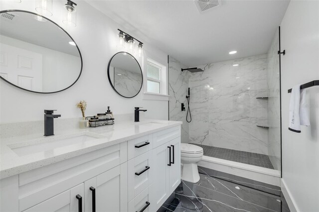 bathroom with a tile shower, vanity, and toilet