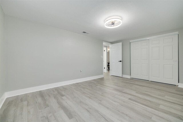 unfurnished bedroom with light hardwood / wood-style flooring and a closet