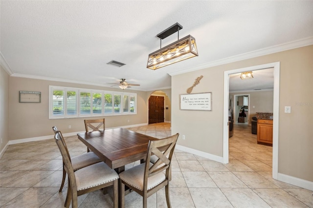 dining space with light tile patterned flooring, a textured ceiling, ceiling fan, and ornamental molding