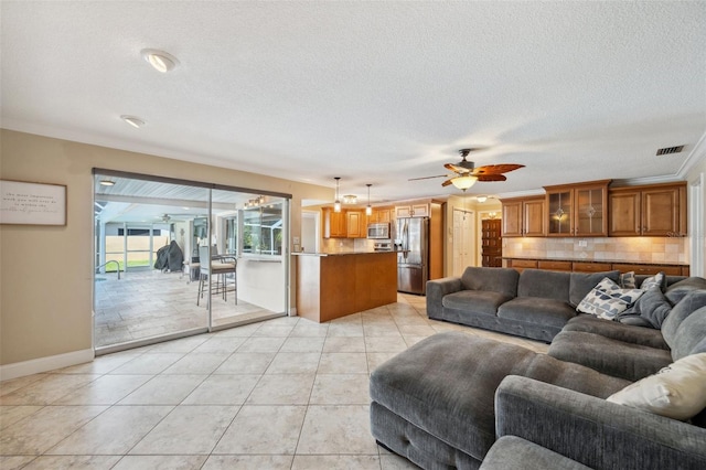 living room featuring a textured ceiling, ceiling fan, ornamental molding, and light tile patterned floors