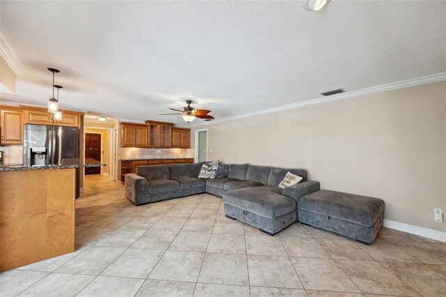 living room featuring ornamental molding, light tile patterned floors, a textured ceiling, and ceiling fan