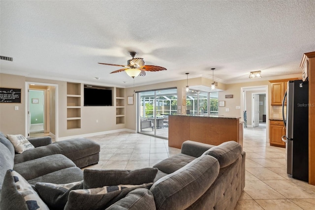 living room with ceiling fan, built in shelves, light tile patterned floors, and a textured ceiling