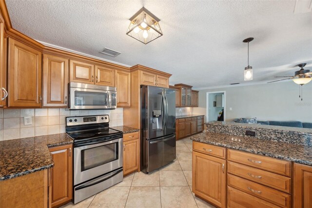 kitchen with light tile patterned flooring, a textured ceiling, ceiling fan, stainless steel appliances, and decorative backsplash