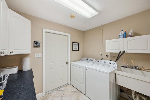 laundry area with light tile patterned floors, washer and clothes dryer, sink, and cabinets