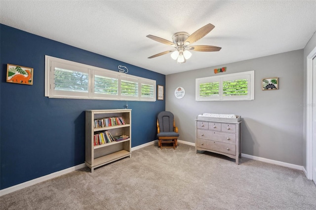 sitting room with light carpet, a textured ceiling, and ceiling fan