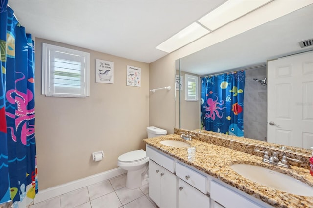 bathroom with dual vanity, tile patterned floors, toilet, and a wealth of natural light