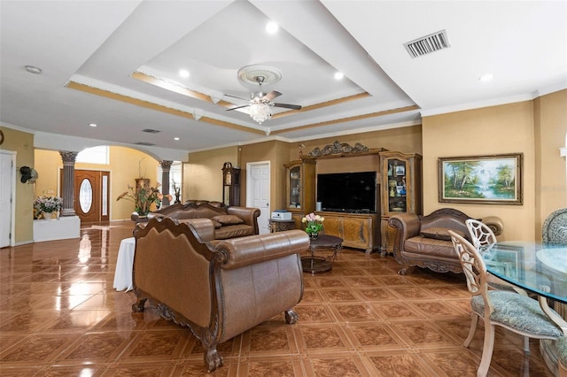 tiled living room featuring ornamental molding, decorative columns, ceiling fan, and a raised ceiling