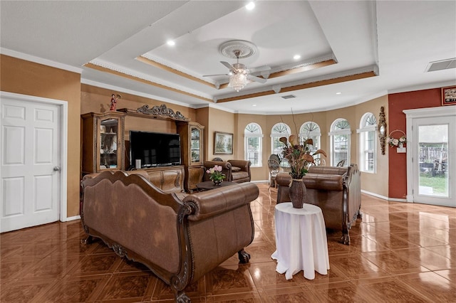 tiled living room with a tray ceiling, ornamental molding, and ceiling fan