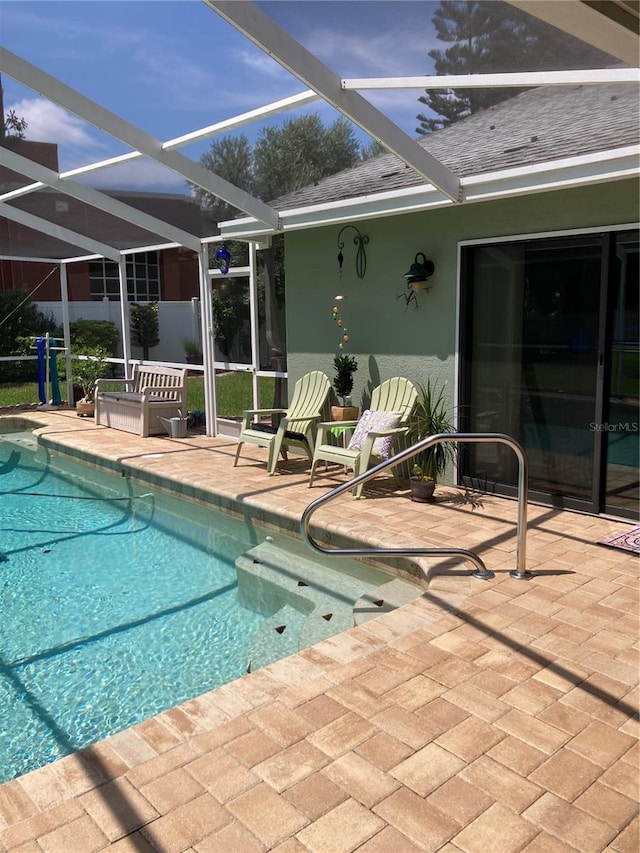 view of pool with glass enclosure and a patio area