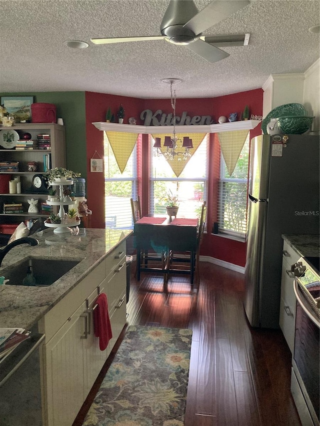 kitchen featuring ceiling fan with notable chandelier, light stone counters, sink, dark hardwood / wood-style floors, and range with electric stovetop