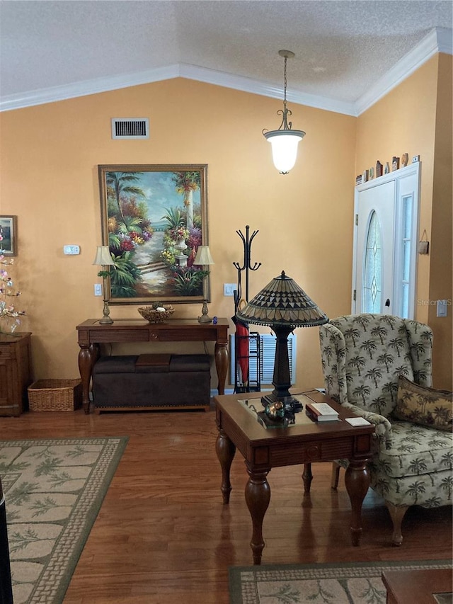 living room featuring a textured ceiling, lofted ceiling, hardwood / wood-style floors, and crown molding