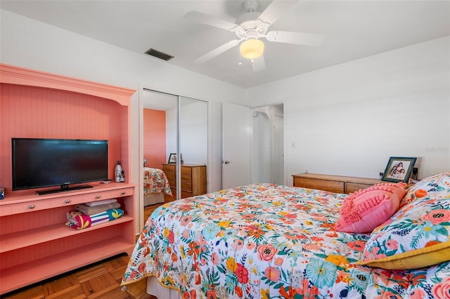 bedroom with parquet floors, ceiling fan, and a closet