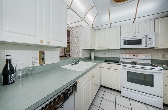 kitchen with light tile patterned floors, sink, white cabinets, and white appliances