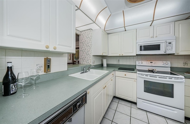 kitchen with white appliances, decorative backsplash, white cabinets, and a sink