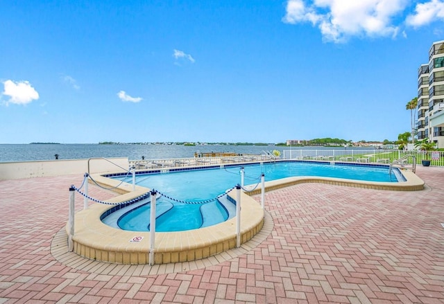 community pool featuring a water view and fence