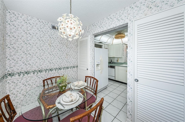 dining area with a textured ceiling, light tile patterned floors, and a chandelier