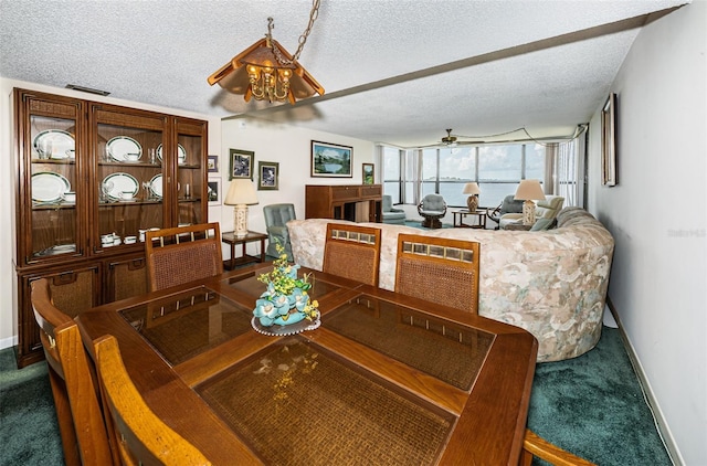 carpeted dining room featuring a textured ceiling, ceiling fan with notable chandelier, and a water view