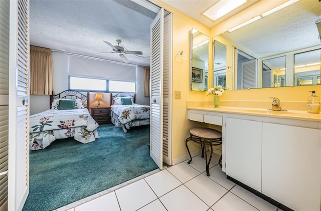 bathroom featuring ceiling fan, vanity, tile patterned flooring, and a textured ceiling