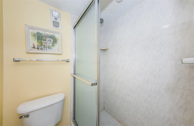 bathroom featuring toilet, a textured ceiling, and a shower with door