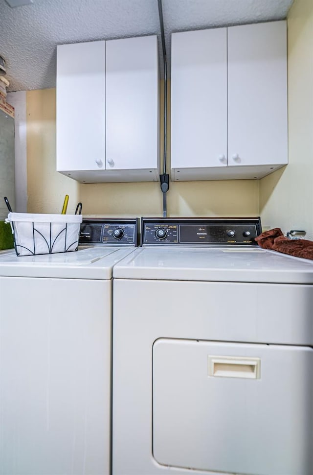 laundry room featuring a textured ceiling, cabinets, and washer and clothes dryer