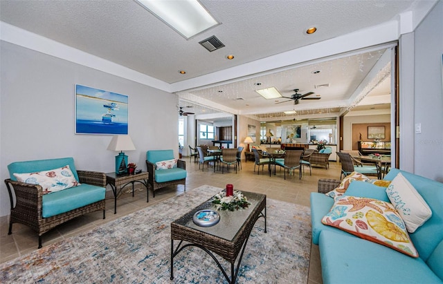 tiled living room featuring ceiling fan and a textured ceiling