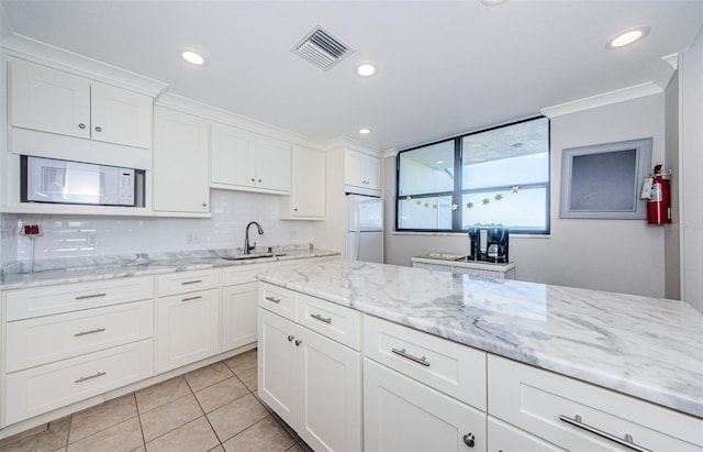 kitchen featuring sink, crown molding, white appliances, white cabinetry, and light stone counters