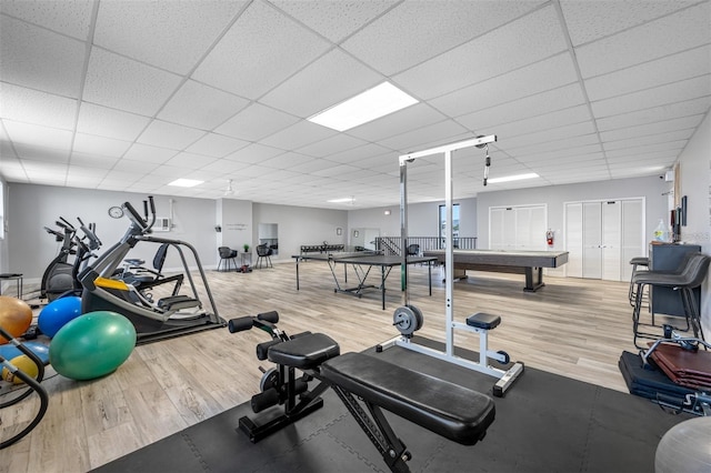 exercise area with a paneled ceiling and light hardwood / wood-style flooring