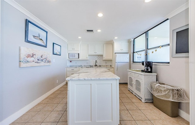 300 Woodette Dr Unit 202B, Dunedin, FL 34698 - kitchen with white appliances, crown molding, white cabinetry, a center island, and light tile patterned floors