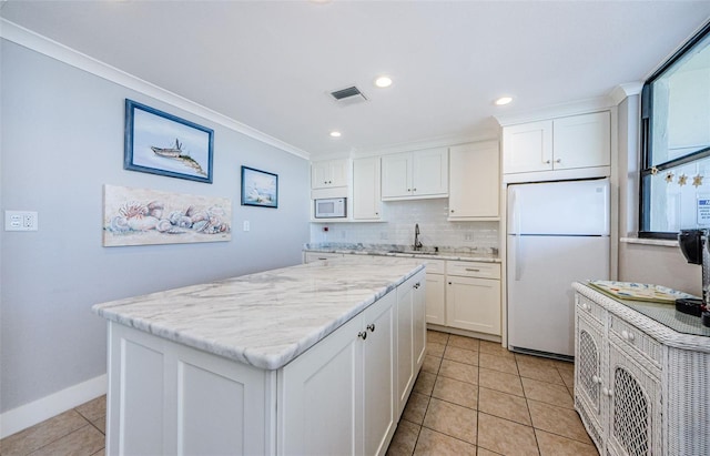 300 Woodette Dr Unit 202B, Dunedin, FL 34698 - kitchen featuring white appliances, crown molding, light tile patterned flooring, a center island, and white cabinetry