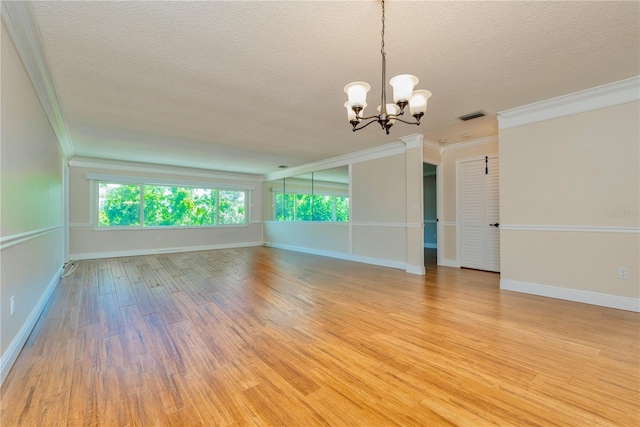 unfurnished living room featuring light wood-type flooring, a textured ceiling, an inviting chandelier, and crown molding