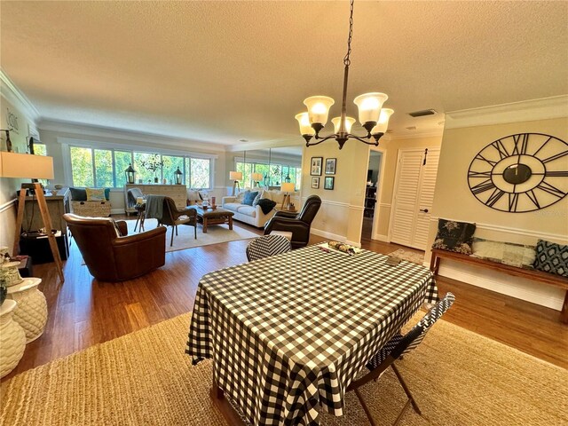 dining space with a notable chandelier, ornamental molding, and hardwood / wood-style flooring