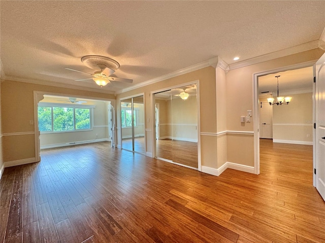 unfurnished room featuring a textured ceiling, crown molding, ceiling fan with notable chandelier, and hardwood / wood-style flooring