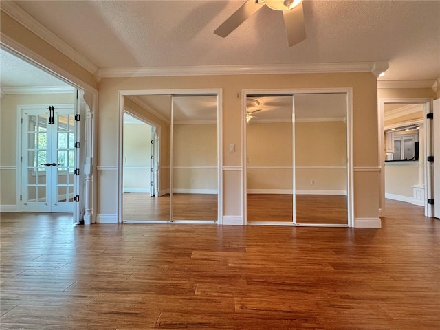 unfurnished living room with hardwood / wood-style flooring, a textured ceiling, french doors, and crown molding