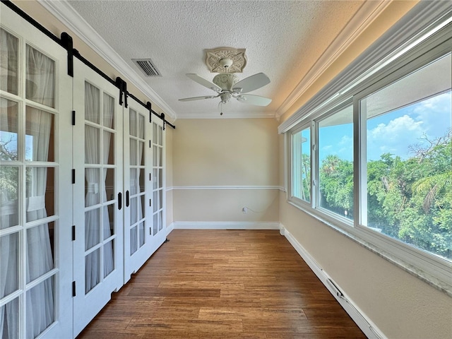 unfurnished room featuring crown molding, a barn door, and wood-type flooring