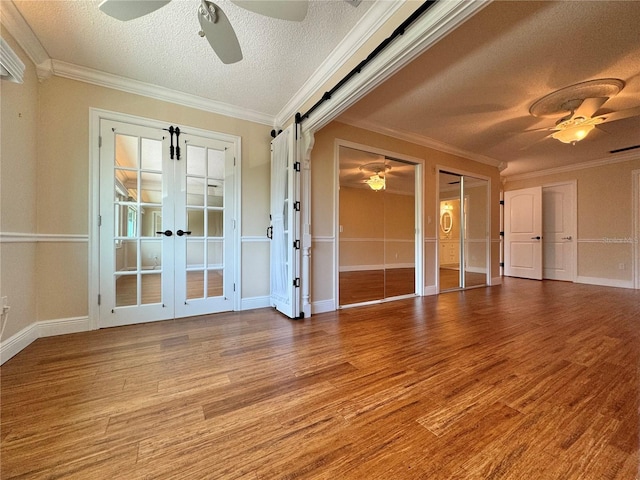 unfurnished room featuring ceiling fan, crown molding, wood-type flooring, and french doors