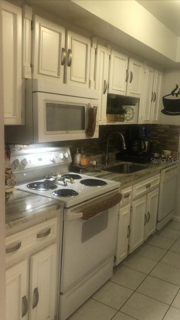 kitchen featuring sink, white appliances, white cabinets, and light tile patterned flooring