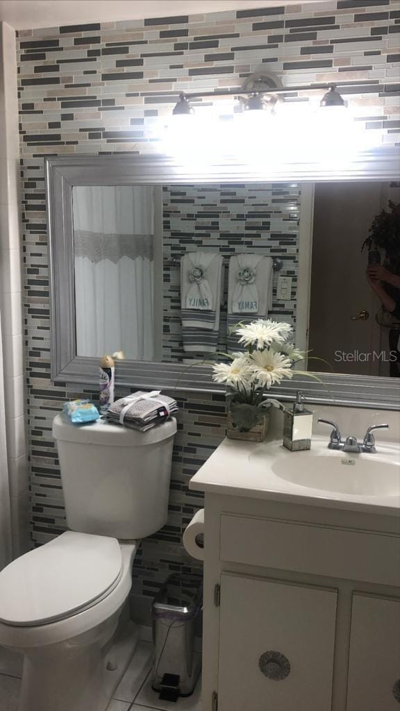 bathroom featuring toilet, tile patterned floors, tile walls, and vanity