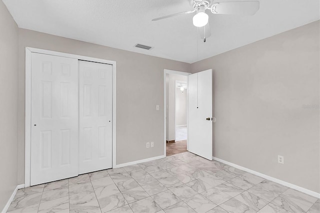 unfurnished bedroom with ceiling fan, a textured ceiling, and a closet