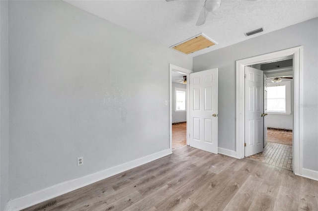 unfurnished bedroom featuring light wood-type flooring, ceiling fan, a textured ceiling, and multiple windows